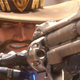 A cowboy with a mechanical arm aims a large pistol.